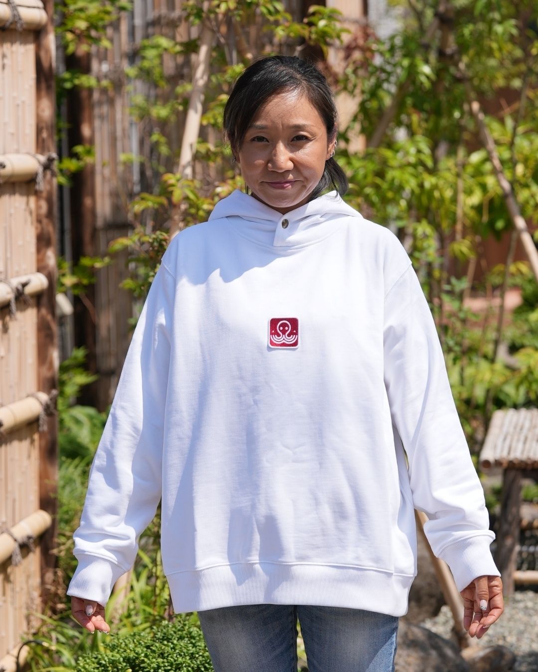 Akiko présentant les manches et la coup du hoodie blanc Basics, de la marque Tous Imparfaits