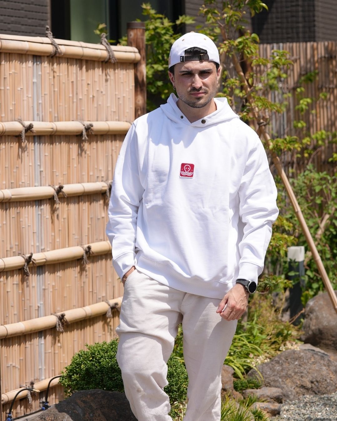 Le hoodie blanc Basics de Tous Imparfaits, porté par un modèle homme en extérieur