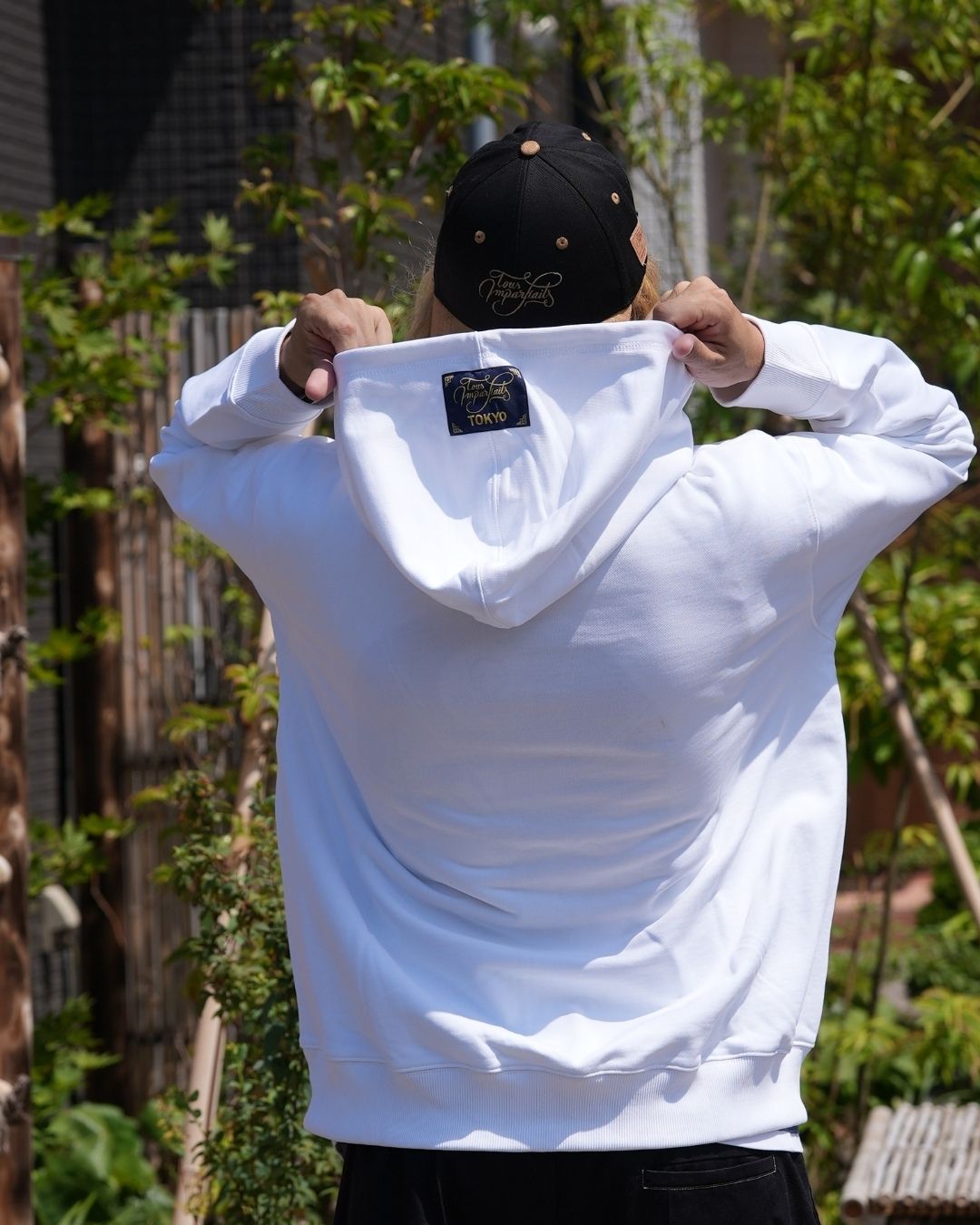 Le hoodie blanc Basics de Tous Imparfaits, porté par Tev de dos, présentant la capuche