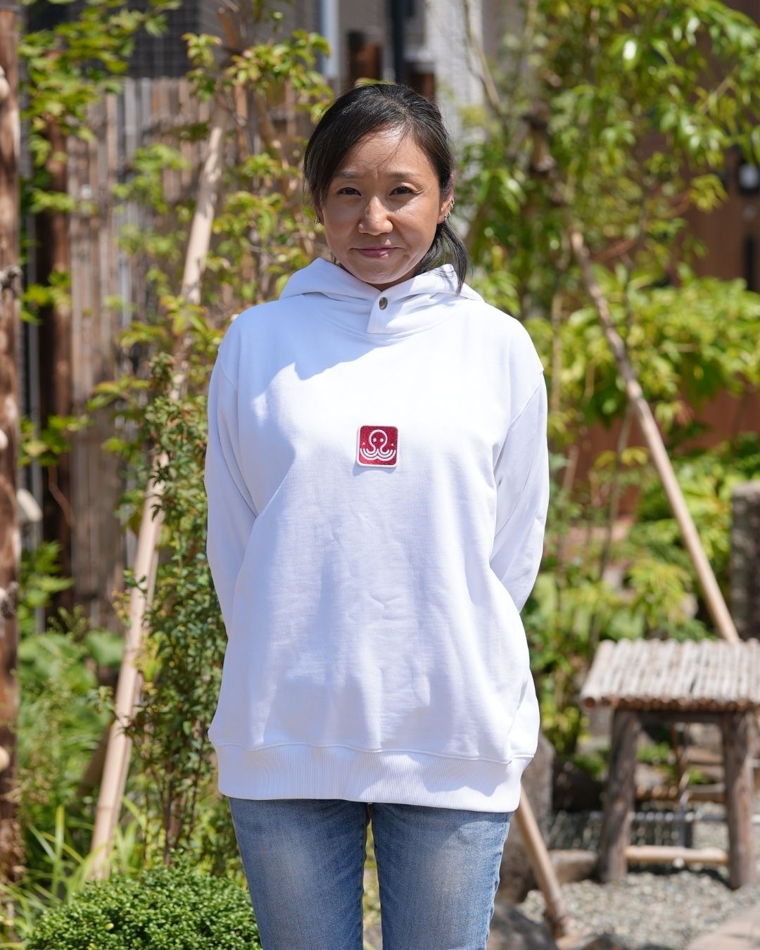 Modèle féminin portant un hoodie blanc Basics de Tous Imparfaits en extérieur