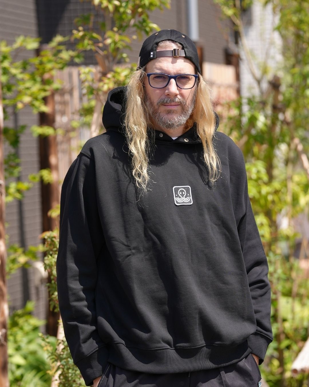Tev Ici Japon, portant le hoodie Basics noir Tous Imparfaits