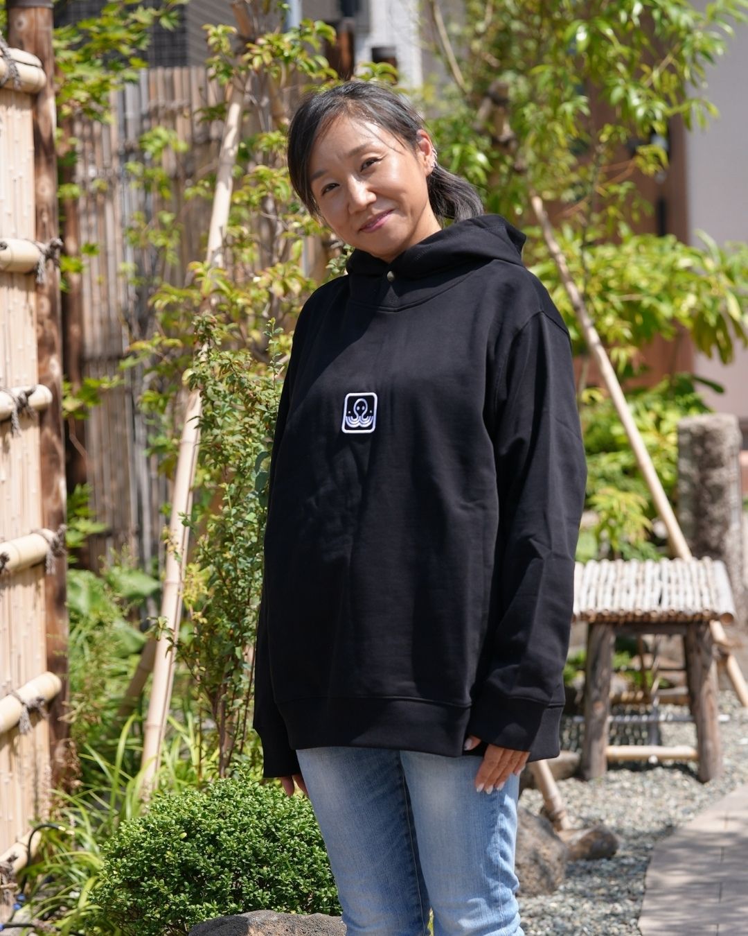 Modèle féminin portant le hoodie Basics noir, en extérieur