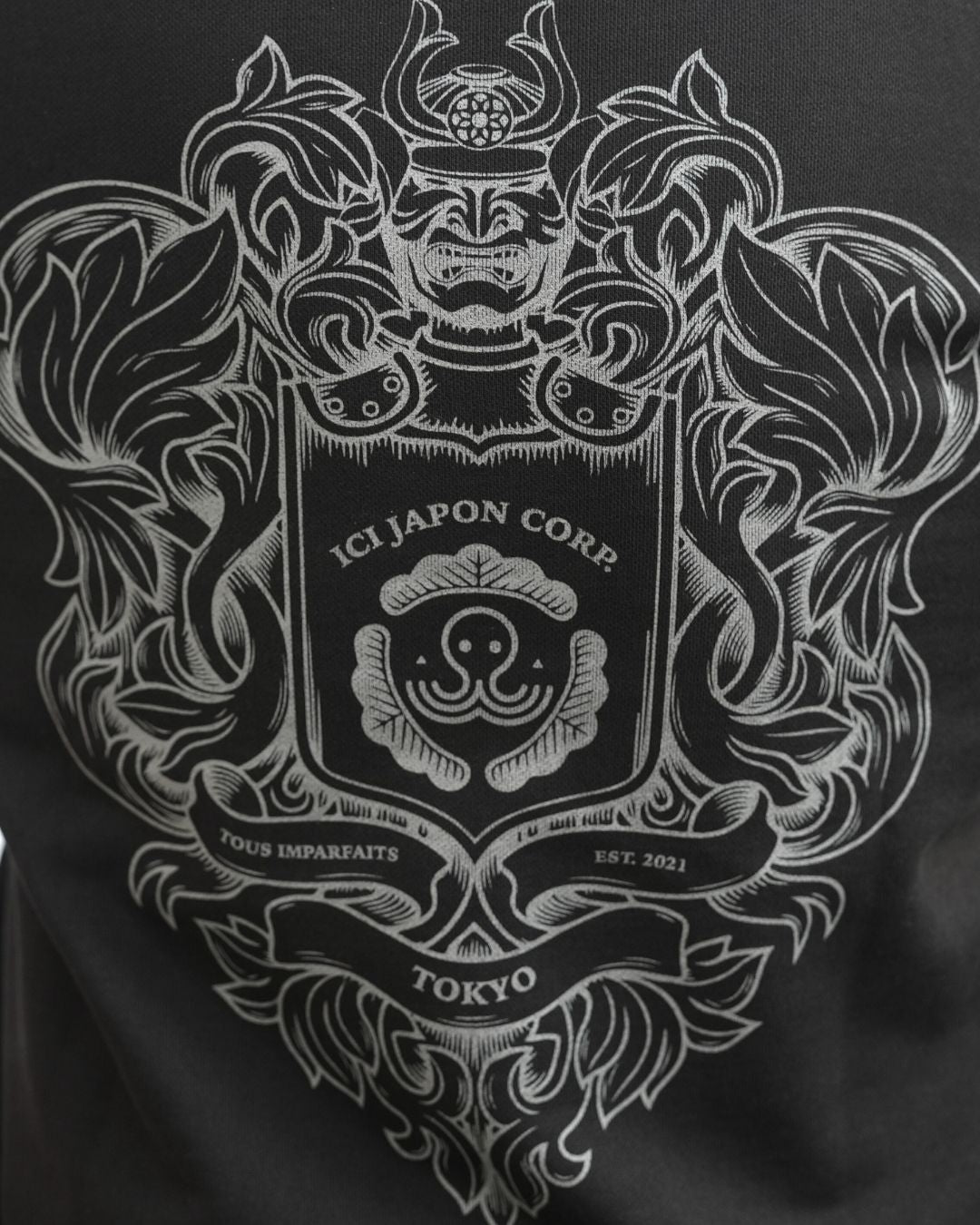 Gros plan sur le motif au dos du hoodie noir University de Tous Imparfaits