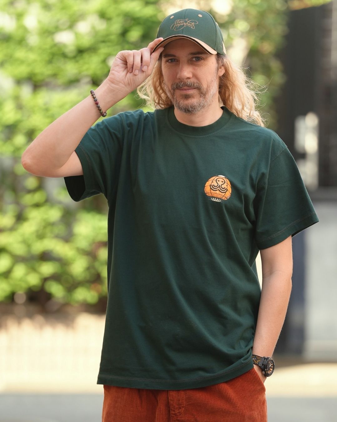 Tev portant le t-shirt Halloween vert, tenant sa casquette Tous Imparfaits verte