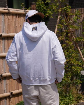 Le hoodie blanc Basics de Tous Imparfaits, porté par un modèle homme de dos en extérieur