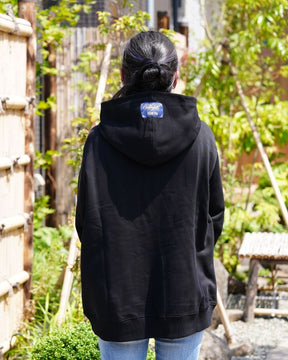 Modèle féminin portant le hoodie Basics noir de dos, en extérieur