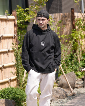 Léo d'Ici Japon Corp portant le hoodie Basics noir en extérieur