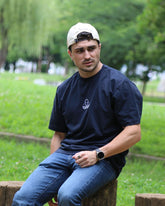 Léo assis en extérieur, avec le t-shirt bleu Basics de Tous Imparfaits