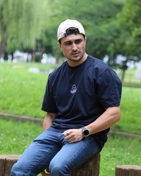 Léo assis en extérieur, avec le t-shirt bleu Basics de Tous Imparfaits
